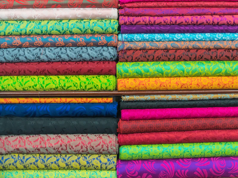 Muestrario de tejidos y telas de distintos colores sobre una mesa de trabajo