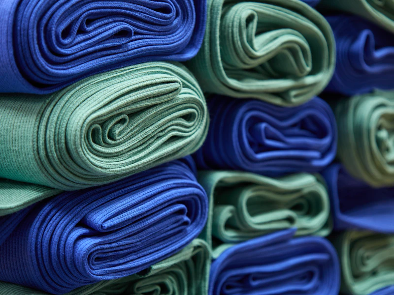 Tejidos de algodón doblados en tonos azules apilados en una estantería